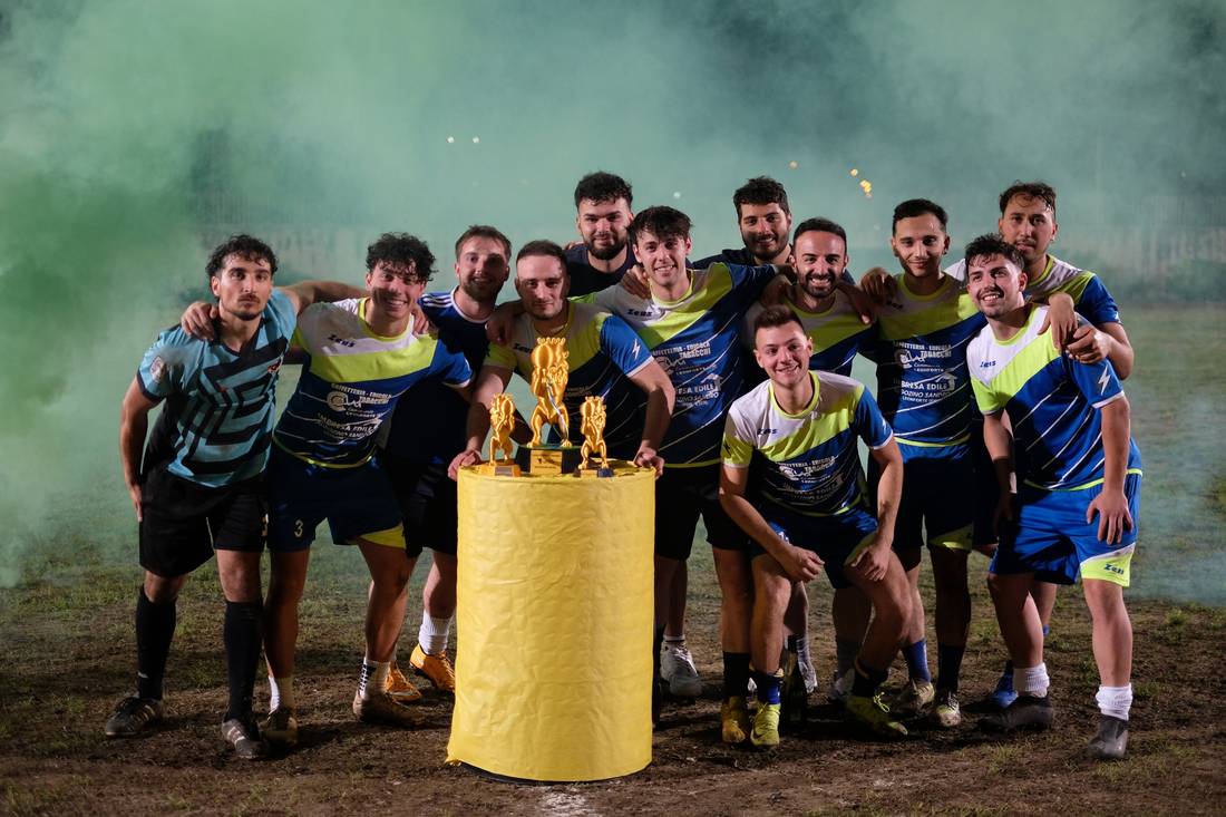 Foto di squadra con i trofei, tra il fumo verde
